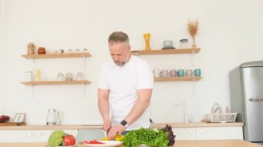 Bir adam mutfakta karısına taze organik sebze salatası hazırlıyor. Vejetaryenler için sağlıklı yiyecekler