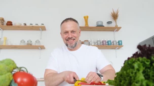 ベジタリアンの男性は 有機野菜のサラダを準備し カメラで笑っている 野菜からの健康食品 4Kビデオ — ストック動画