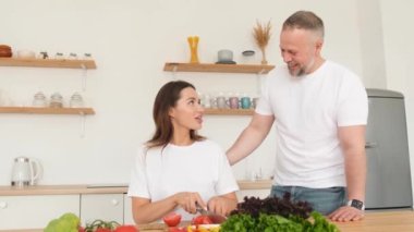 Ailesi için yemek pişiren mutlu bir kadın, aile içinde samimi bir sevgi. Anne baba, kız ve oğul mutfakta birlikteler.