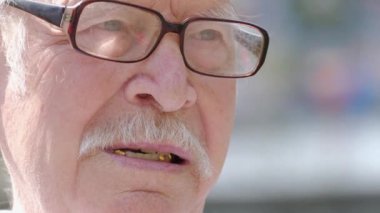 Büyükbabanın yüzünü kapat, gözlük takıyor, kameraya bakıyor. Yaşlı beyaz saçlı adam