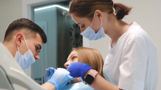 Gabinecie Dentystycznym Lekarz Asystent Leczą Zęby Młodej Kobiety Terminowe Leczenie — Wideo stockowe