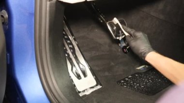 Arabayı iyice temizleyin. Eldiven takan bir adam arabanın pedallarını fırçalar.