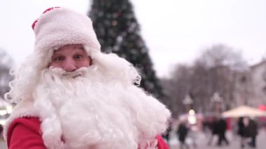 Noel Baba başparmağını kaldırır, adam kameraya bakar ve gülümser, sempatiyle eline odaklanır. İzole. Noel konsepti.