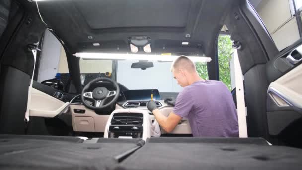 一位年轻的专业工匠坐在汽车的内部 把它擦去污垢 从里面洗车 — 图库视频影像