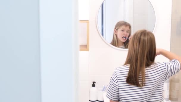 Una Adolescente Cepilla Cuidadosamente Los Dientes Delante Del Espejo Del — Vídeo de stock