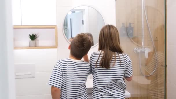 浴室の鏡の前でかわいい男の子と女の子の歯をブラッシングの肖像画 小学生の朝 毎日の衛生 — ストック動画