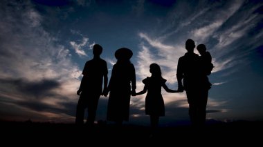 Mutlu aile gün batımında parkta duruyor. Arkadaş canlısı aile kavramı. Genç bir ailenin silueti. 4k video