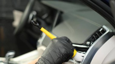 Modern araba temizleme işçisi torpidoyu siliyor. Araba kuru temizleme. Gösterge paneli temizliği. Siyah otomobil paneli kapalı.