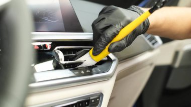 Modern bir arabayı temizleyen, gösterge panelini silen profesyonel bir işçi. Araba kuru temizleme