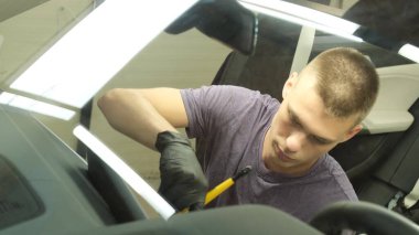 Modern bir arabayı temizleyen, gösterge panelini silen profesyonel bir işçi. Araba kuru temizleme