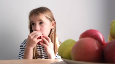 Sarışın çocuk beyaz arka planda elma yiyor. Video Lezzetli Olgun Sonbahar Meyveleri. Çocuklarda vejetaryenlik