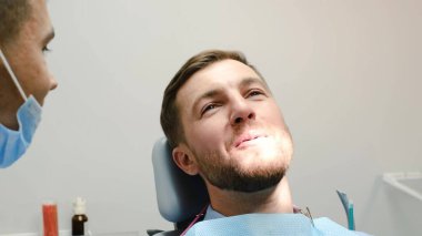 Cheerful young patient of European appearance during a visit to the dentist. The key to healthy teeth