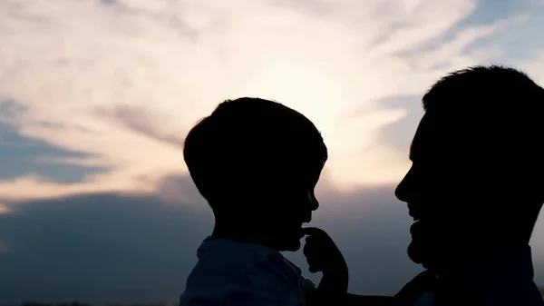 Father and son silhouette on a blue sky background. Happy family child dream concept. A father holds a child in his arms at sunset shadow silhouette. fathers day High quality 4k video