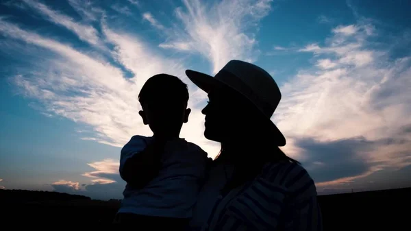 Mother and son silhouette on the background of the blue sky. Happy family child dream concept. A mother holds a child in her arms at sunset. Mothers Day. 4k video