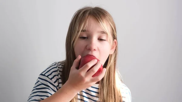 A little girl is eating a red juicy apple. Healthy eating with fruits. 4k video