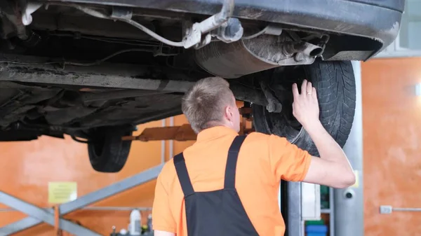 The mechanic repairs the car, checks the wheel hubs of the car. Checks the car in the workshop. Car service