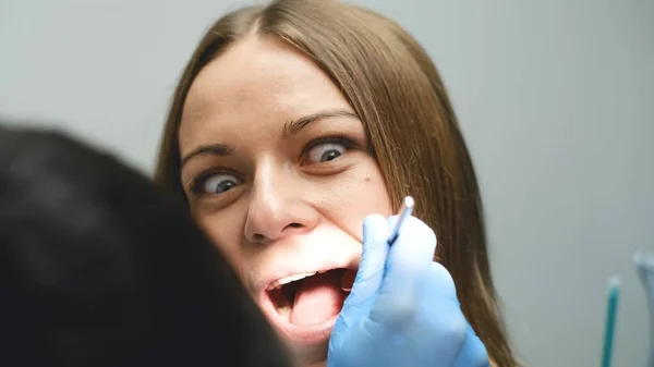 怖がった少女は現代の診療所で歯を治療する 歯医者の臆病と恐怖 歯医者は患者の歯を調べ — ストック写真
