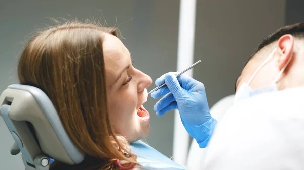 開口部を持つ女性患者の歯科医院で歯を検査し 修理する若い歯科医 — ストック写真