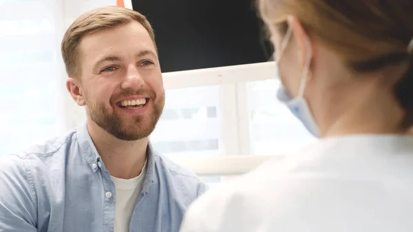Handsome young guy with a snow-white smile in the dentists office. Modern dental treatment