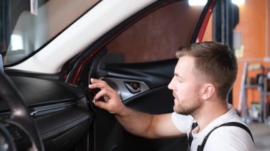 Arabanın teknik durumunu içeriden kontrol ediyorum. Genç profesyonel bir araba tamircisi arabanın içini inceliyor.