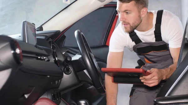 담당하는 자동차 정비사는 태블릿을 사용하여 기술적 상태를 Gps 조종기를 설치하는 — 스톡 사진