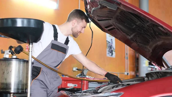 Car service. A satisfied young man is repairing a car with modern tools.