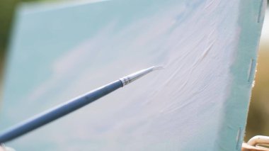 Tuvale resim çizmenin yakın çekimi. Easel, tuval, boya, fırça, spatula, çözücü.