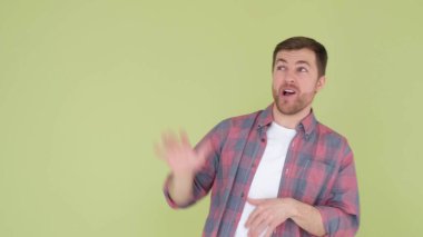European man in a red shirt funny dancing isolated on a background in the studio, a man rejoices and raises his hands up. Happy person