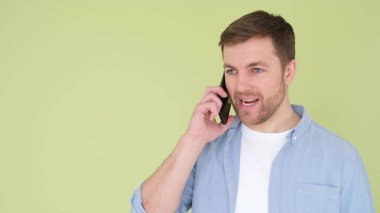 Angry man talking on smartphone isolated on background in studio. Arguing or solving a problem, annoyed man have a cell phone conversation to manage work trouble, middle frame shot