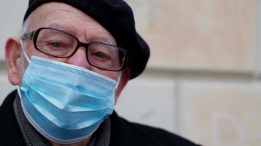 Portrait of an old grandfather in a protective mask against viruses, he looks into the camera. Threat of influenza virus infection. Coronavirus Pandemic COVID-19