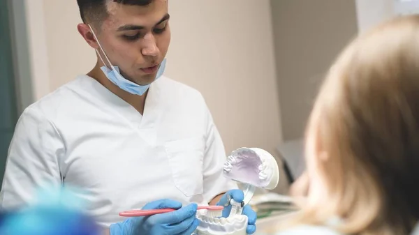 儿童牙医会诊 牙科医生在人体模型上显示如何正确刷牙 预防青少年牙病 — 图库照片
