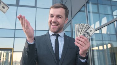 Deli gibi mutlu genç bir adam elinde bir tomar dolarla onları fırlatıyor. Zengin bir bankacı. jack pot