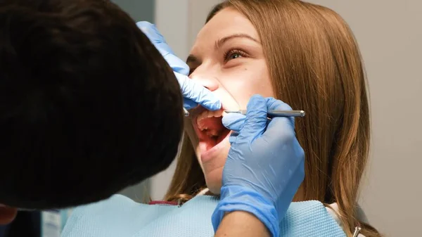 医者は若い女性の歯を歯科器具で治療する 歯のタイムリーな治療 歯の椅子に — ストック写真