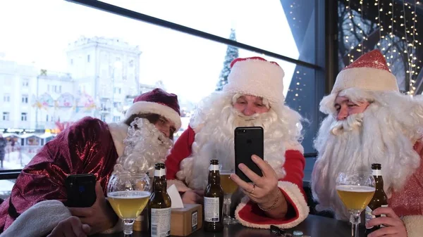 Drei Weihnachtsmänner Blicken Mit Weit Aufgerissenen Augen Auf Den Smartphone — Stockfoto