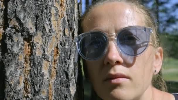 Portrait of a girl with glasses near the tree. Camera zooms out, close-up — Stockvideo