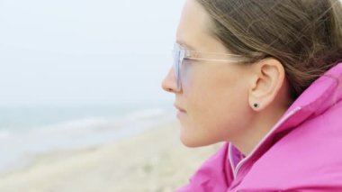 Bir kız sahilde oturuyor ve deniz sörfüne bakıyor. Parallax iğnesi