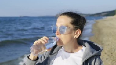 Baykal Gölü 'nün kıyısında Baykal Gölü' nün arka planında duran bir kız, Baykal Gölü 'nün en saf suyunu içiyor. Tatlı su rezervleri