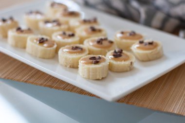 Hızlı ev yapımı aperatif: Kakao parçalı muz kanalı, fıstık ezmesi ve kahve. Lezzetli, sağlıklı yemek.