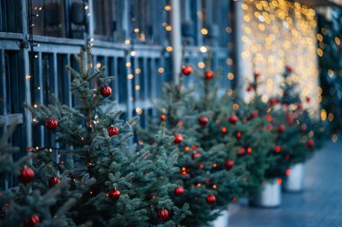 Oyuncaklarla süslenmiş Noel ağacı, arka planda yanan çelenkler kırmızı topları olan güzel, lüks Noel ağacı, pencerenin arka planında koni şeklinde yakın plan. Noel havası.