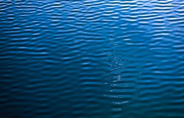 Smooth water blue. water background and sun reflections. textured surface. aerial view. Water surface with waves and ripples as background