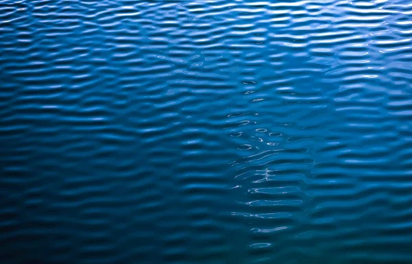Smooth water blue. water background and sun reflections. textured surface. aerial view. Water surface with waves and ripples as background