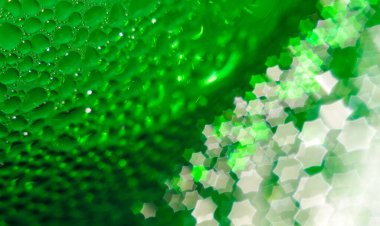 Green glass bottle, selective focus, beautiful blurred bokeh. Close-up. Drops of water on the glass passing in the bokeh in the form of a hexagonal star