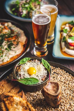 İki bardak bira, bir büyük patatesli gözleme ve siyah arkaplan üzerine sade ahşap masa üzerinde fırınlanmış kabak ile etli tartar servis edilir. Geleneksel tarif.