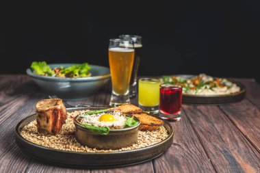 İki bardak bira, bir büyük patatesli gözleme ve siyah arkaplan üzerine sade ahşap masa üzerinde fırınlanmış kabak ile etli tartar servis edilir. Geleneksel tarif.