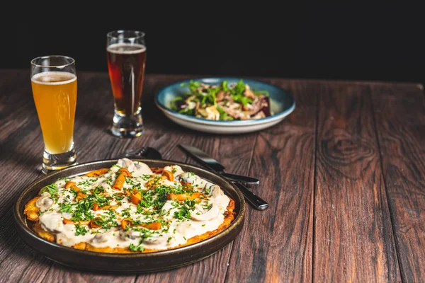 İki bardak bira ve sonbahar ya da kırsal ahşap masada siyah arka planda düşen yiyecekler. Bira, buğday, koyu hafif bira, bira konsepti. Ekim Festivali.