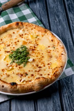 Taze roka ve farklı peynir çeşitleriyle dilimlenmiş lezzetli pizza. Dört peynirli pizza, pizza Margarita. Köy ahşap masasında servis edilmiş. İtalyan mutfağı kavramı.