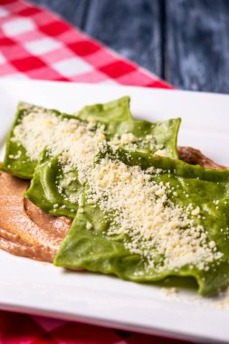 Beyaz bir tabakta sosisli ıspanaklı ravioli. Geleneksel İtalyan mutfağı, kırsal ahşap masa üzerinde. Sağlıklı lezzetli yemek..