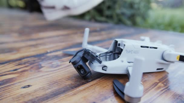 Mens hands lift the broken drone from the wooden floor. — Stock Video