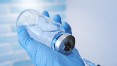 Mavi eldivenli bir doktor ya da hemşire şırınganın içine ilaç atar. Sağlık doktoru aşıyı bir şırıngaya çeviriyor..