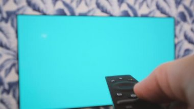 İnsanlar Chroma Key TV izleyip uzaktan kumandalı kanal sörfü yaparak kanal değiştiriyorlar. TV uzaktan kumandası elinde.